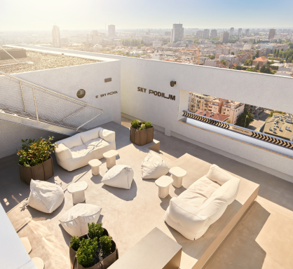A rooftop terrace with white furniture and a city view.